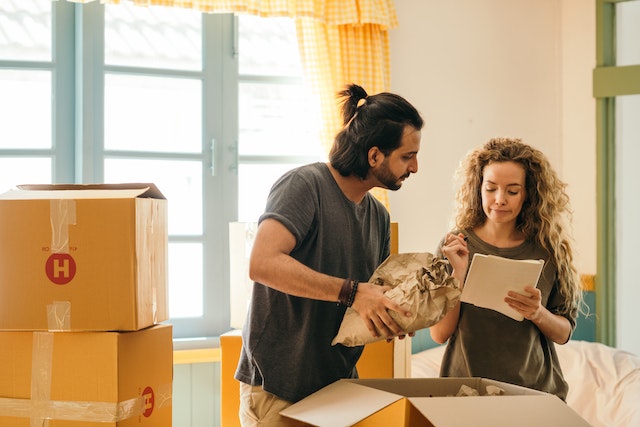 two people looking over a list as their pack up moving boxes