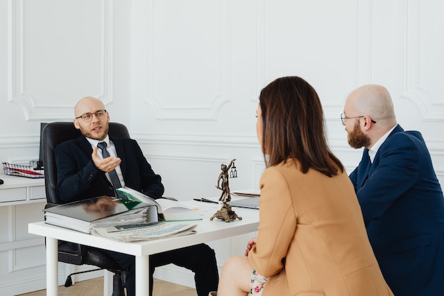 two people sitting across from a lawyer in a white office