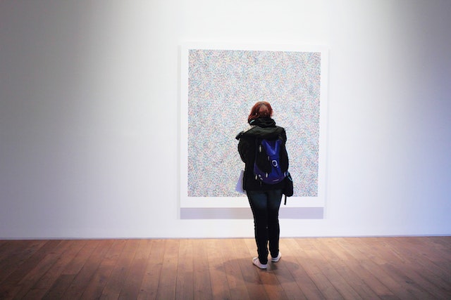 person standing in front of a wall-mounted painting