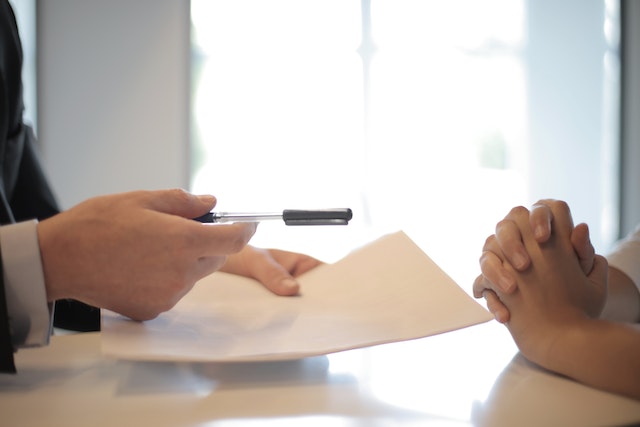 person-handing-person-paperwork-to-sign