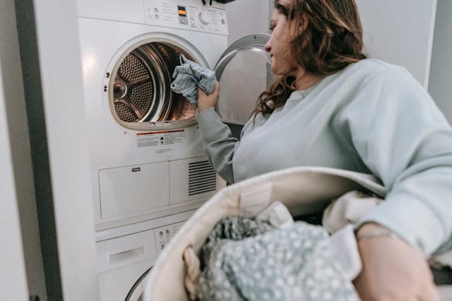 person-holding-a-laundry-hamper-putting-clothes-into-the-washing-machine