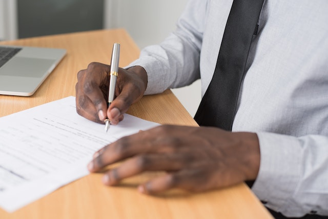 hand-holding-a-silver-pen-to-sign-the-bottom-of-a-letter