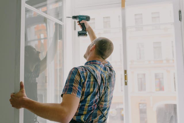 man drilling into open window pane