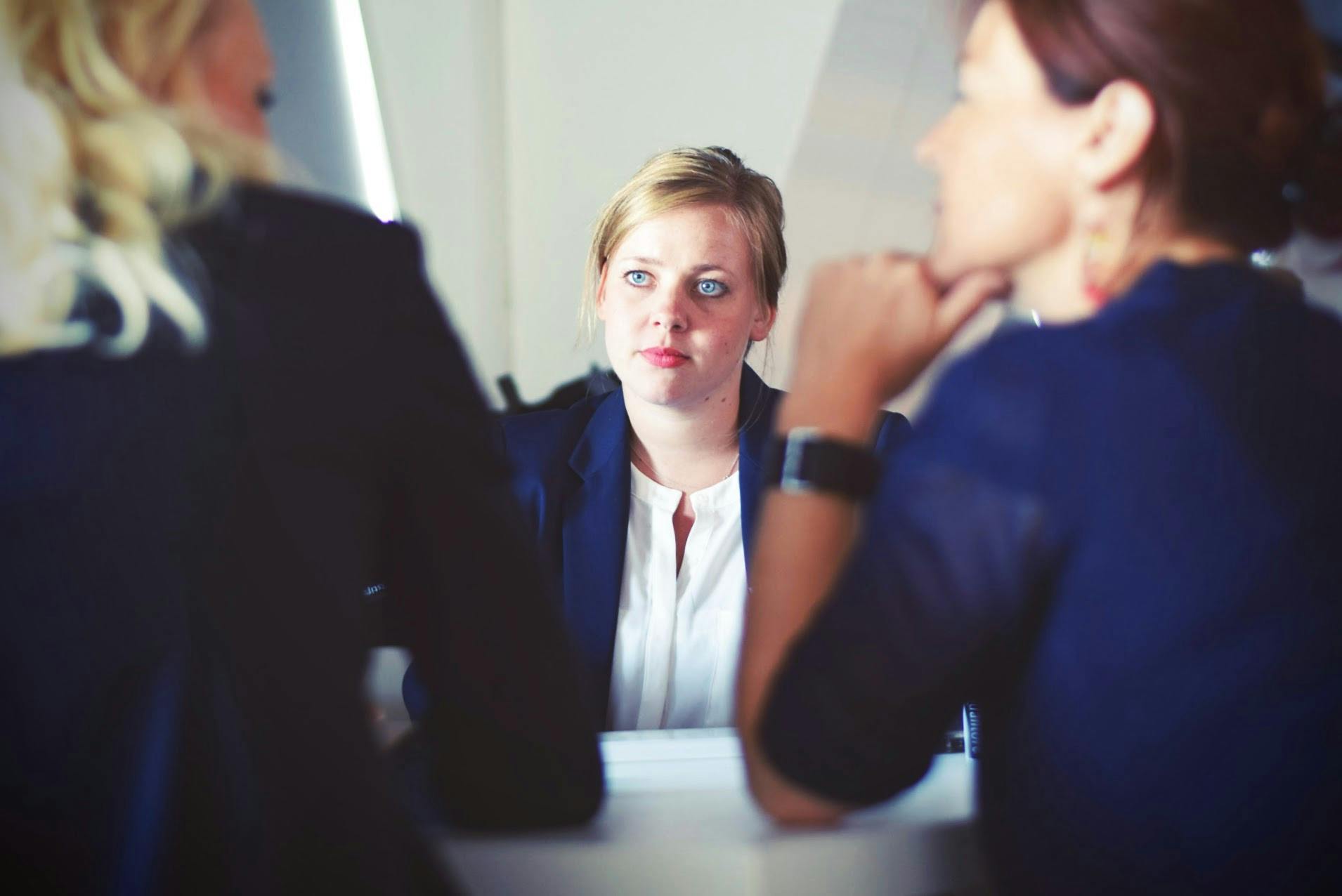 A woman sitting across the table from two other women having a conversation.