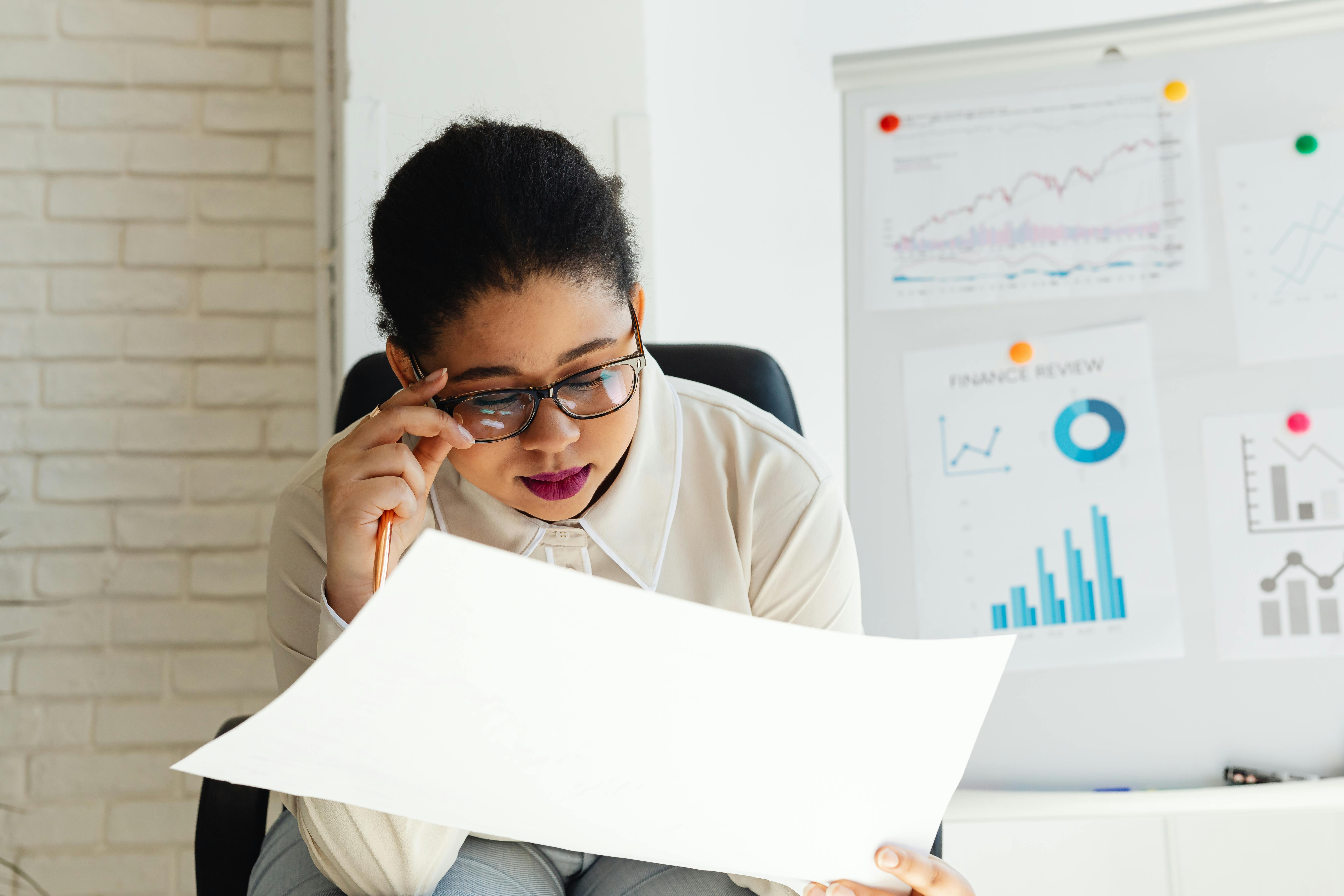 A woman at a desk studying data on graphs and charts.