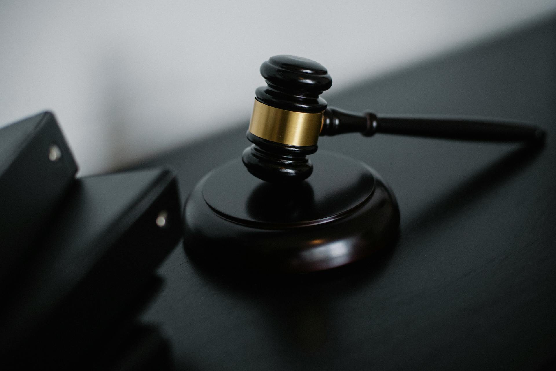 A black and gold judge's gavel on a black desk.