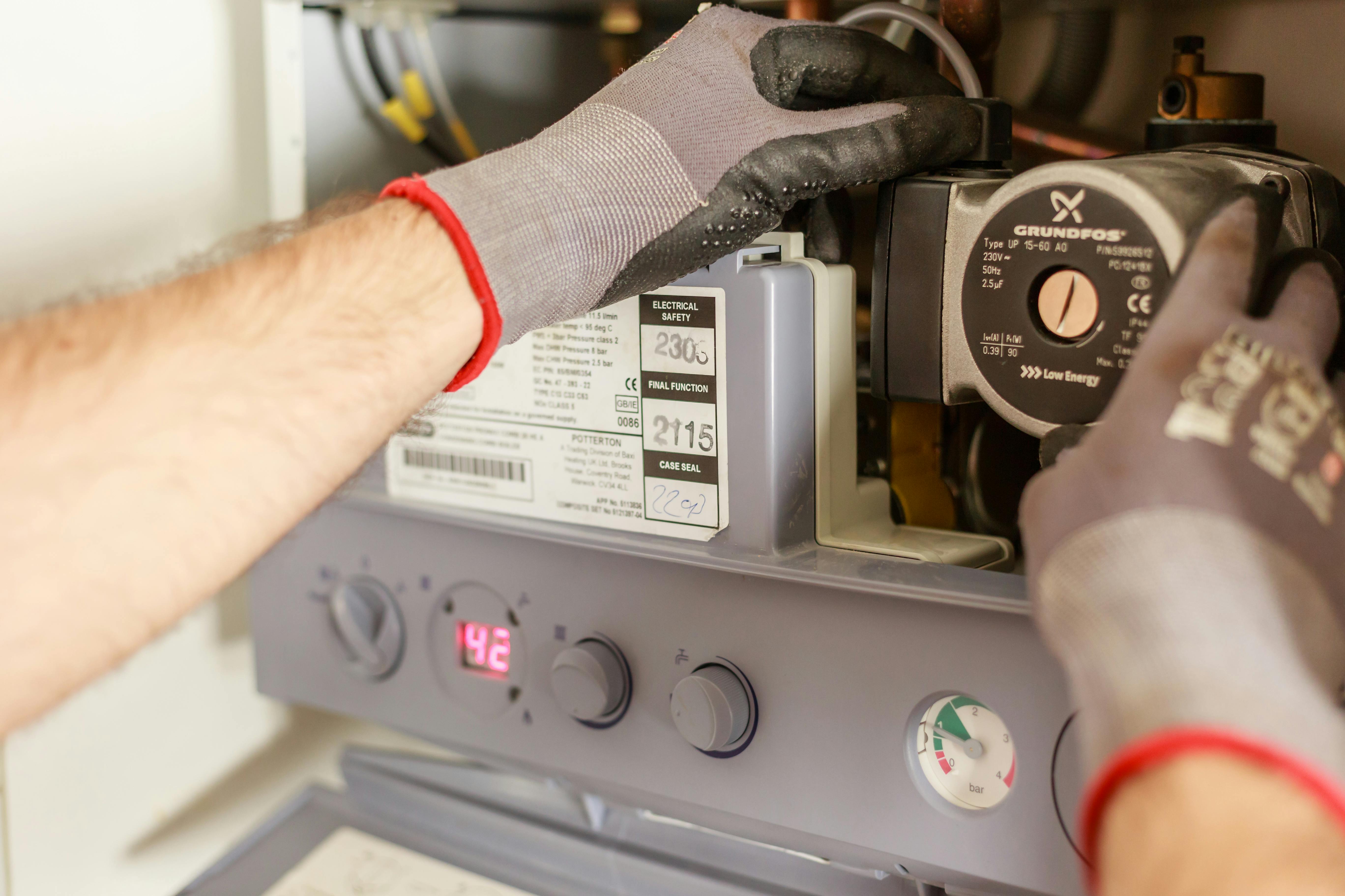 Two gloved hands work on a washing machine.